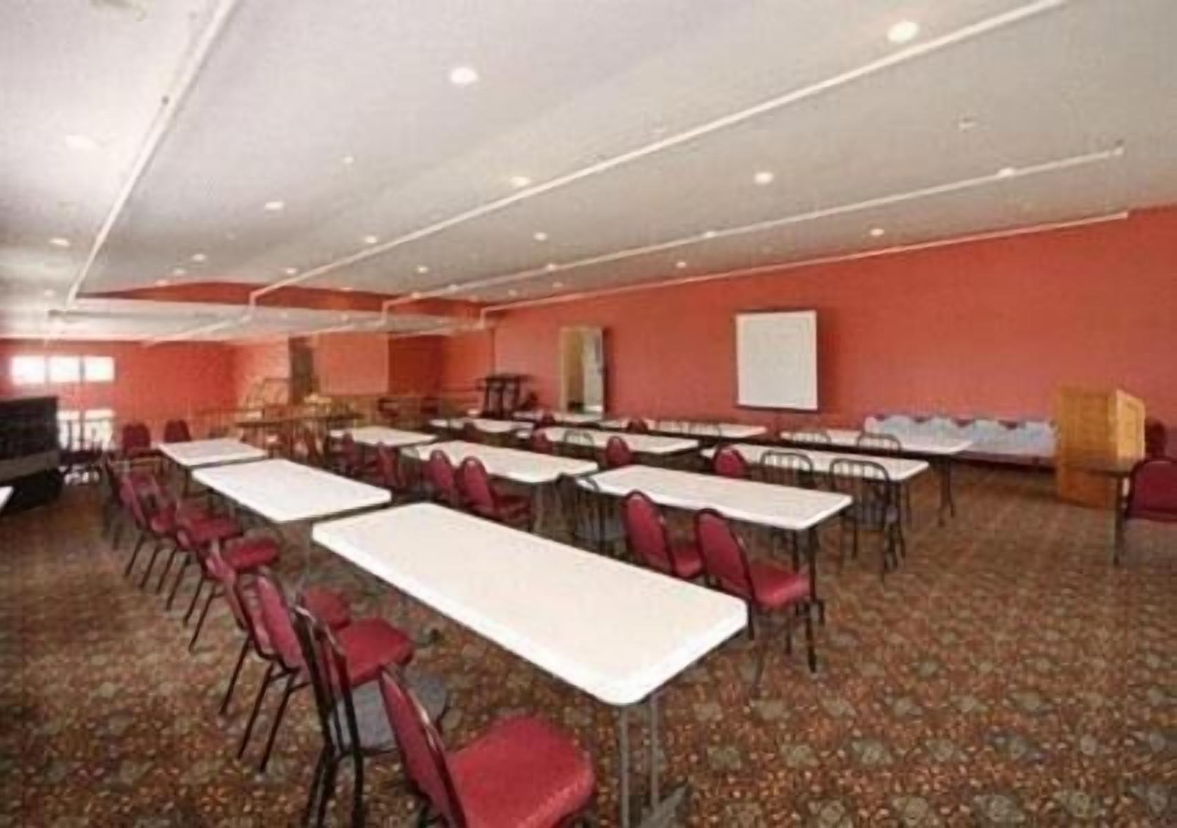 A conference room with multiple tables and chairs, a whiteboard, and a carpeted floor.