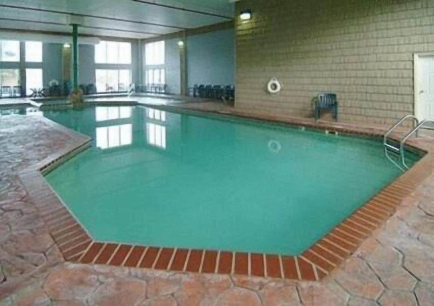 An indoor swimming pool with a tiled floor and a brick wall.