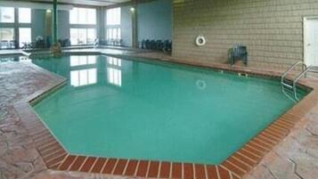 An indoor swimming pool with a tiled floor and a brick wall.