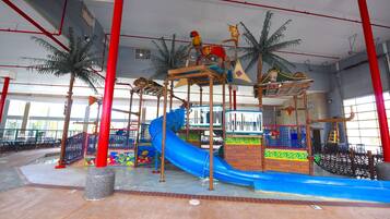 Parque aquático coberto com toboáguas, estruturas de escalada e palmeiras.
