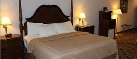 A neatly made bed with a wooden headboard, two bedside tables with lamps, and a carpeted floor.