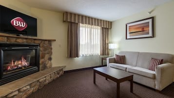 A living room with a stone fireplace, a flat-screen TV, a sofa, and a framed picture on the wall.
