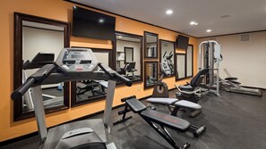 Une salle de sport équipée de tapis de course, d’un banc et d’appareils de musculation.