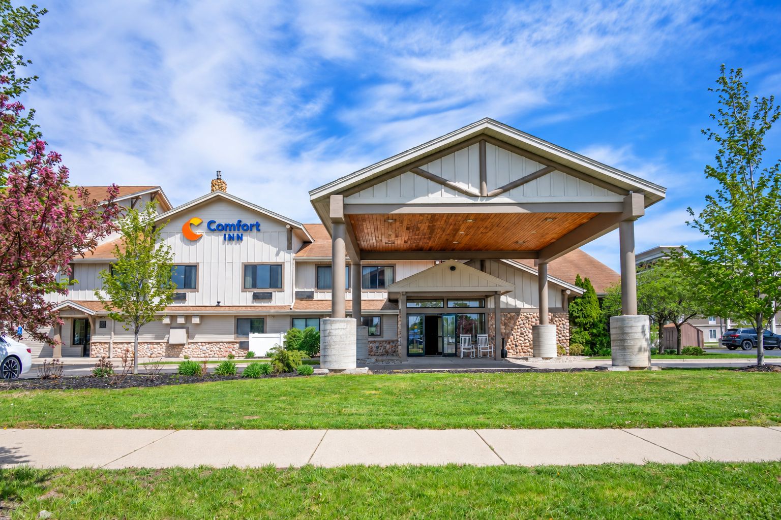 A Comfort Inn hotel with a covered entrance, stone facade, and a parking area.