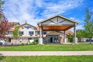 A Comfort Inn hotel with a covered entrance, stone facade, and a parking area.