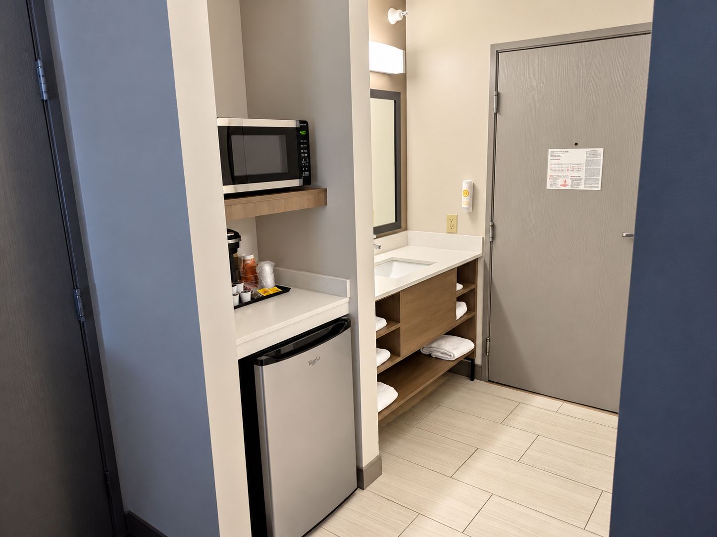 A compact bathroom with a microwave, sink, and storage shelves.