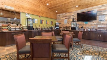 A restaurant with wooden ceiling and walls, a buffet counter, and a TV mounted on the wall.