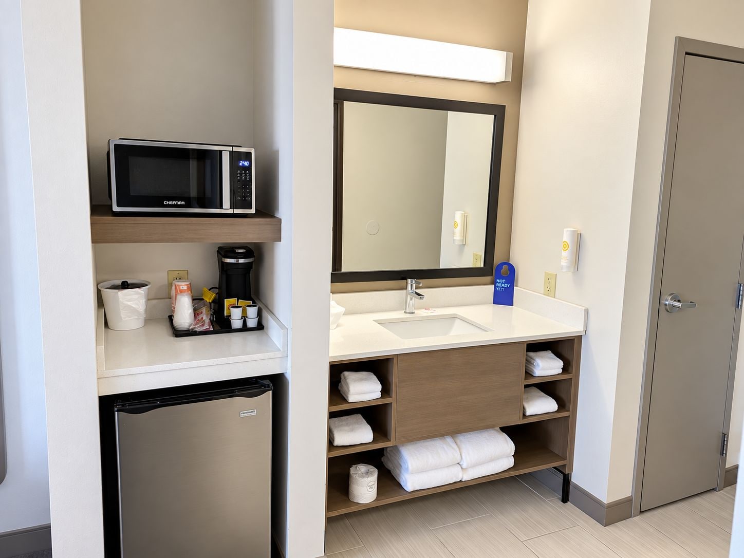 Une salle de bain d’hôtel équipée d’un four à micro-ondes, d’une machine à café, d’un lavabo et d’un espace pour ranger les serviettes.