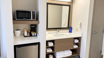 Une salle de bain d’hôtel équipée d’un four à micro-ondes, d’une machine à café, d’un lavabo et d’un espace pour ranger les serviettes.