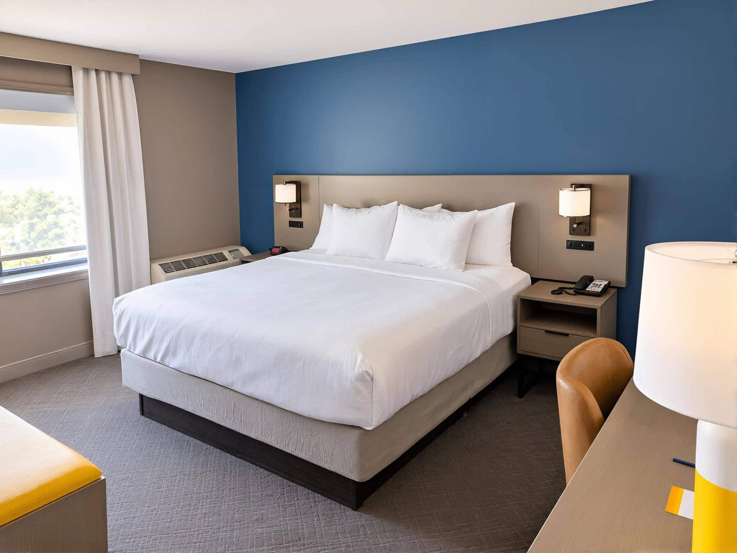 A hotel room with a large bed, bedside tables, a desk, and a chair.