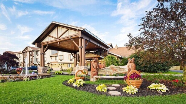 Un hotel con un área exterior cubierta, estatuas de piedra y un jardín bien cuidado.