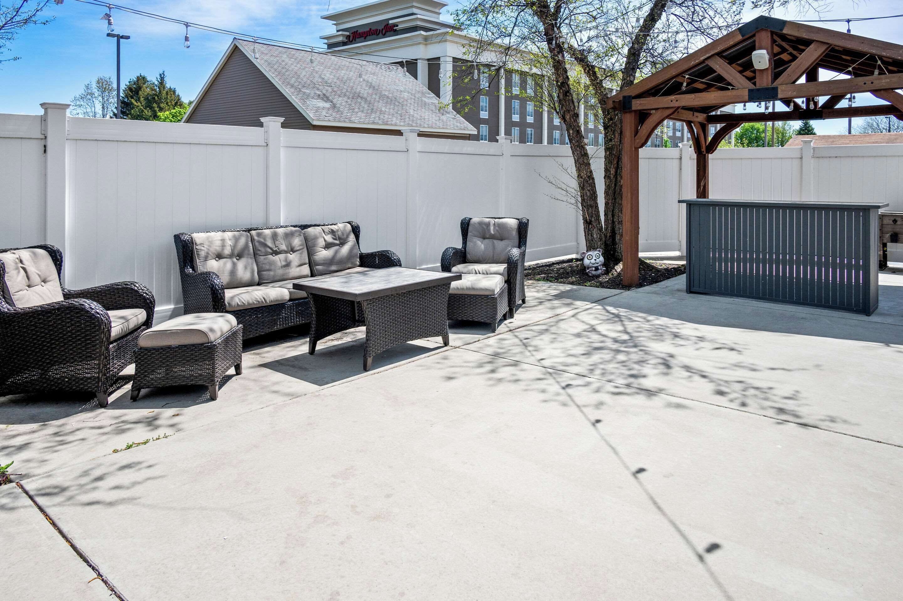 Une terrasse extérieure avec des meubles en osier, une pergola et un abri de jardin.