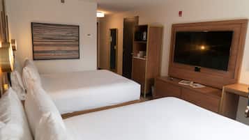 A hotel room with two beds, a TV, a wardrobe, and a painting on the wall.