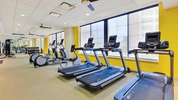 Une salle de sport équipée de tapis de course, de vélos d’exercice et de poids.