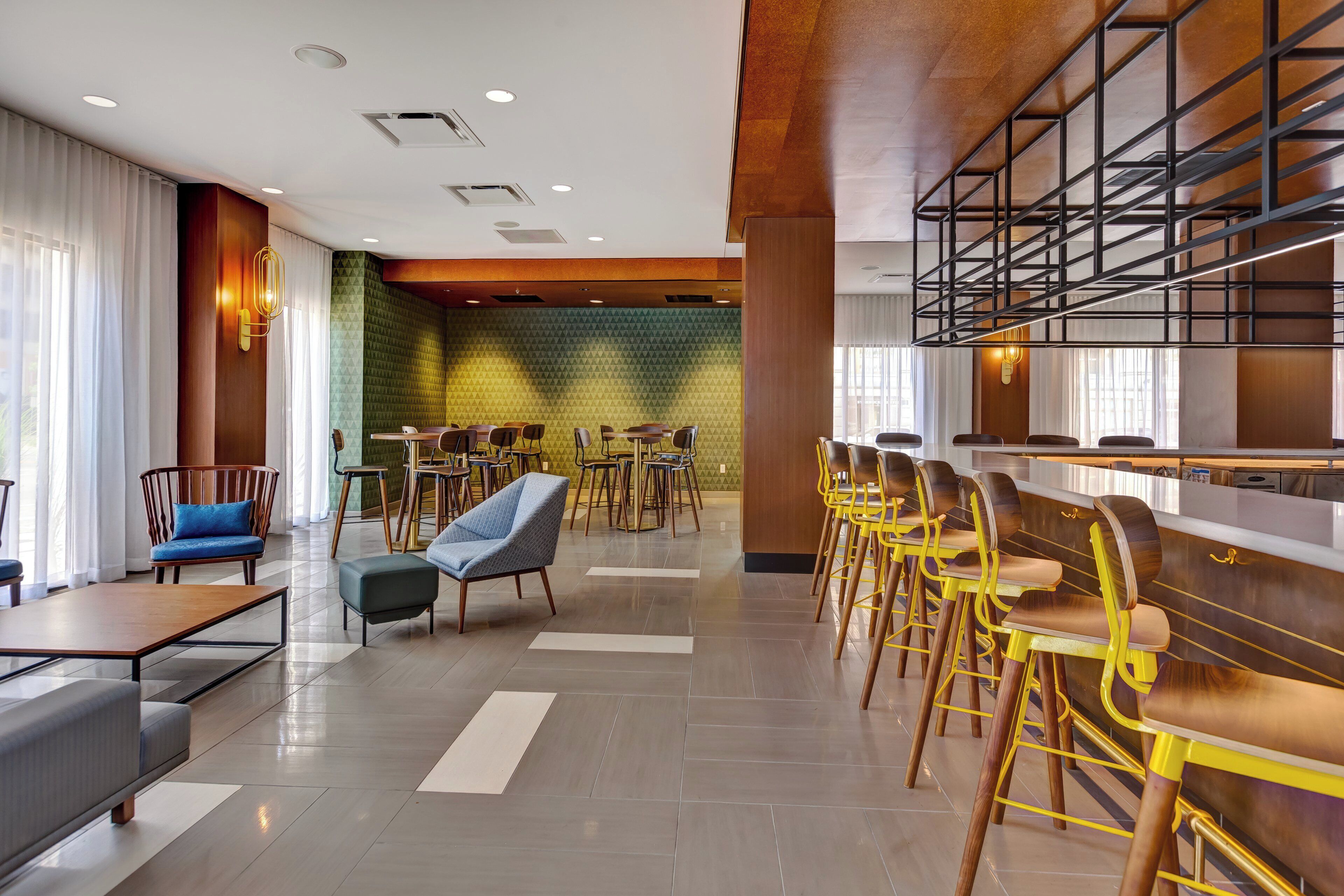 A hotel lobby with a bar area, seating arrangements, and a patterned wall.