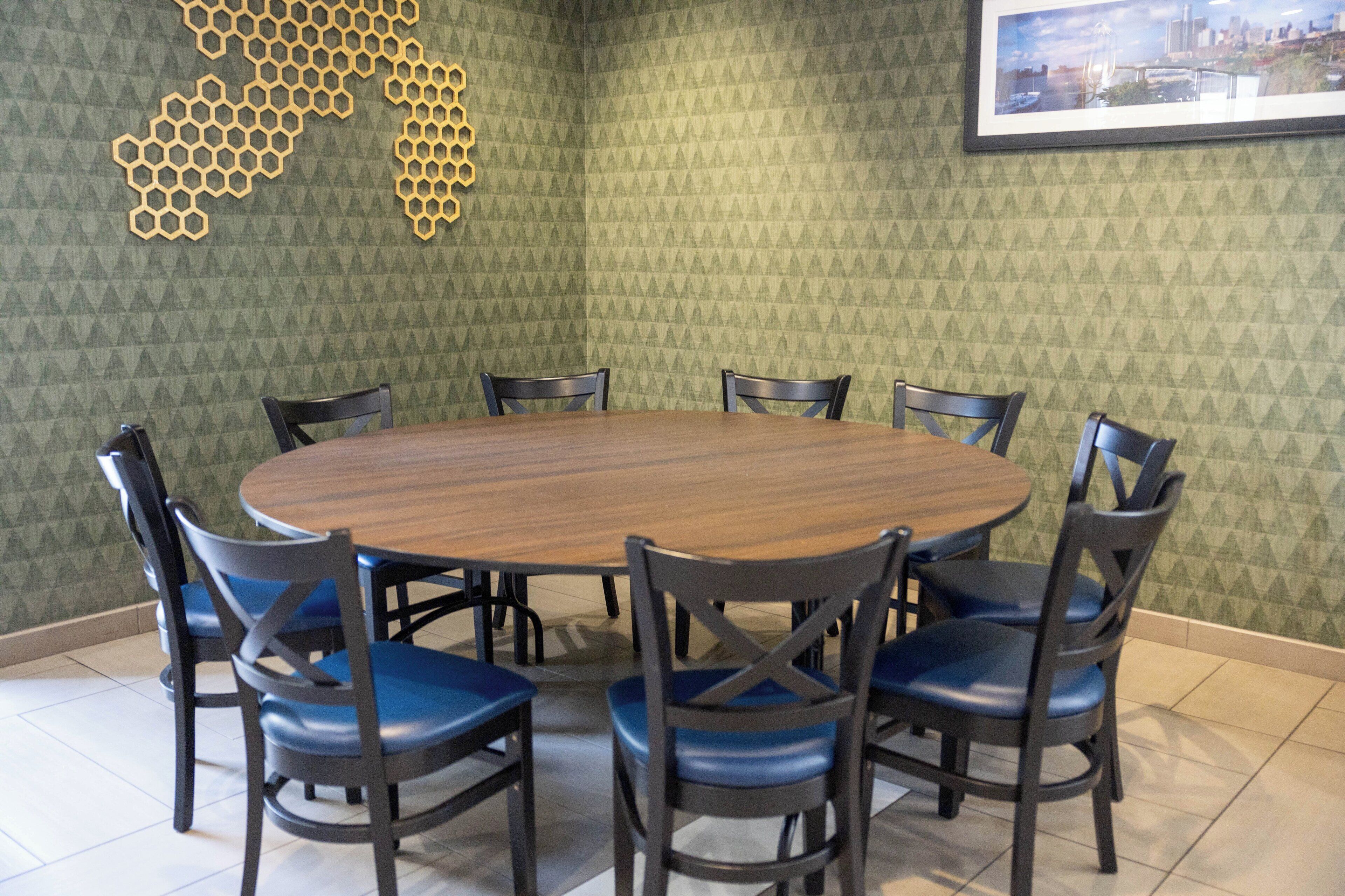 A round table with six chairs, a hexagonal wall decoration, and a framed picture on the wall.