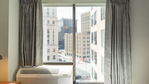 A room with a large window, air conditioning unit, and curtains.