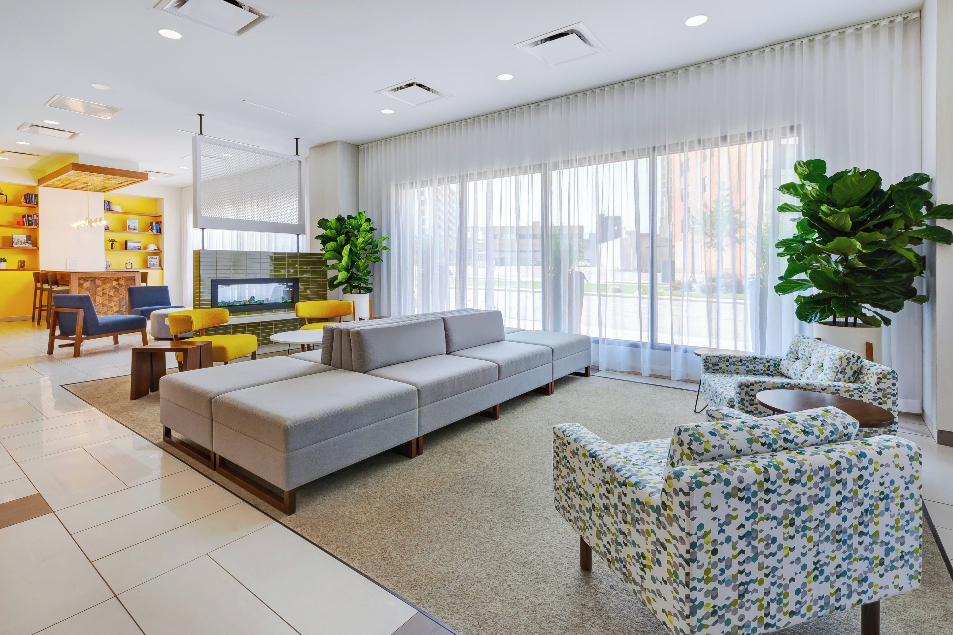 A modern living room with a grey sectional sofa, a patterned armchair, and a television.