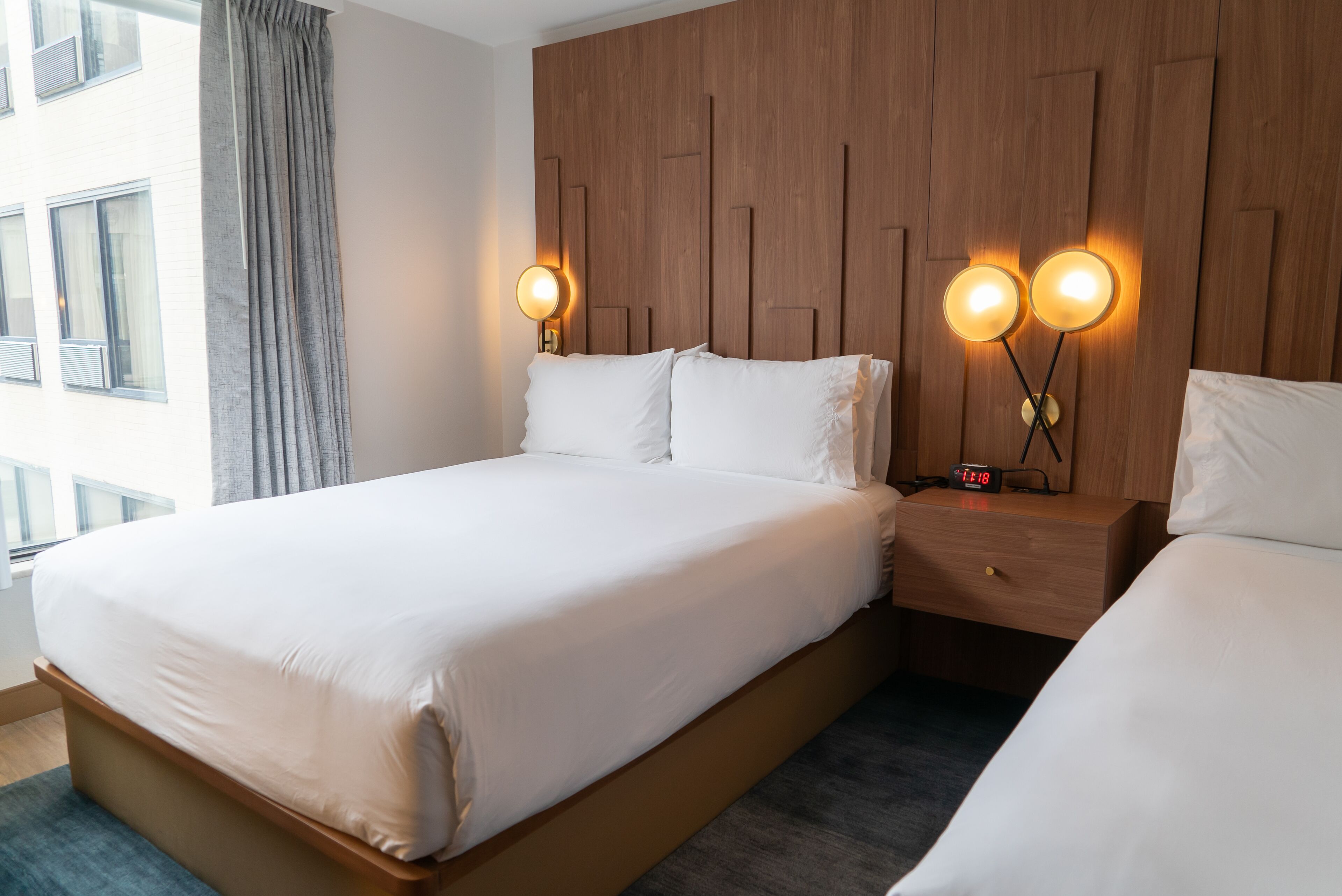 Een moderne hotelkamer met een groot bed, nachtkastjes en een houten hoofdbord.