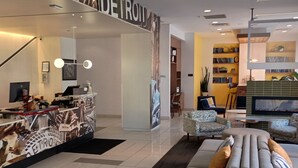 A hotel lobby with a reception desk, seating area, and a large screen TV.