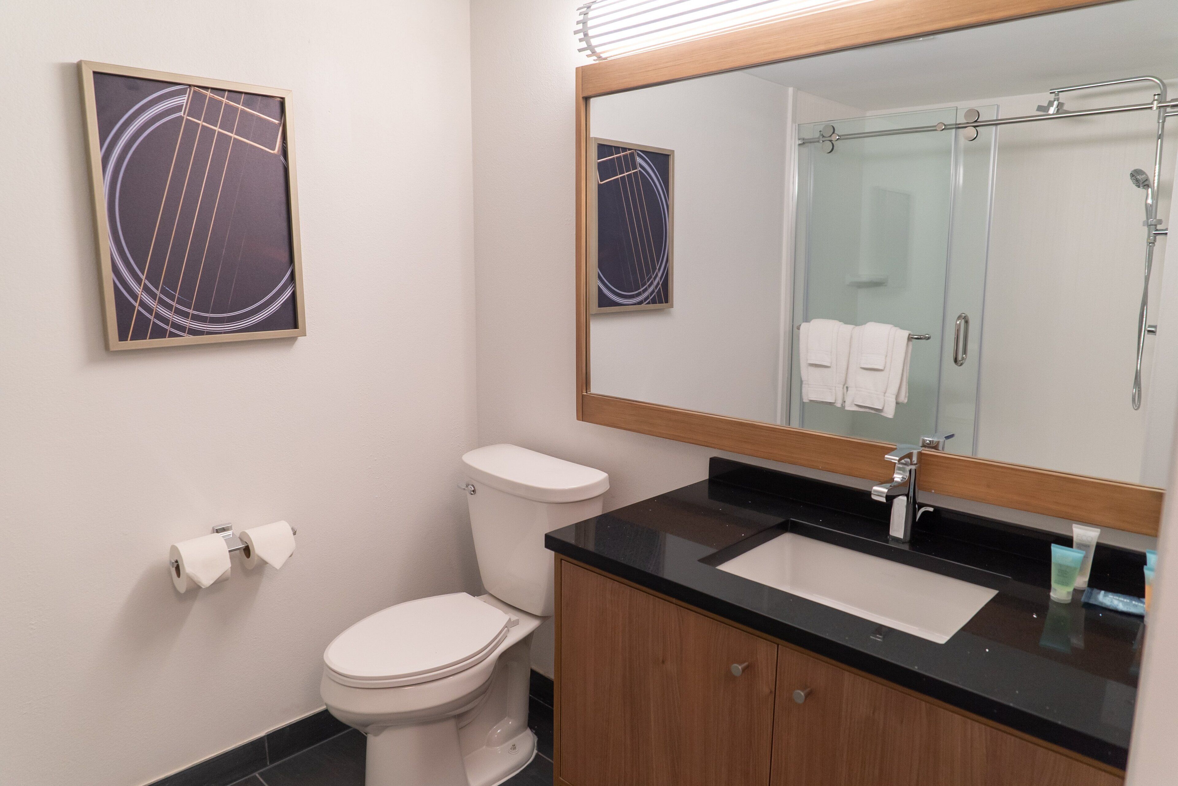 A bathroom with a toilet, sink, and mirror.