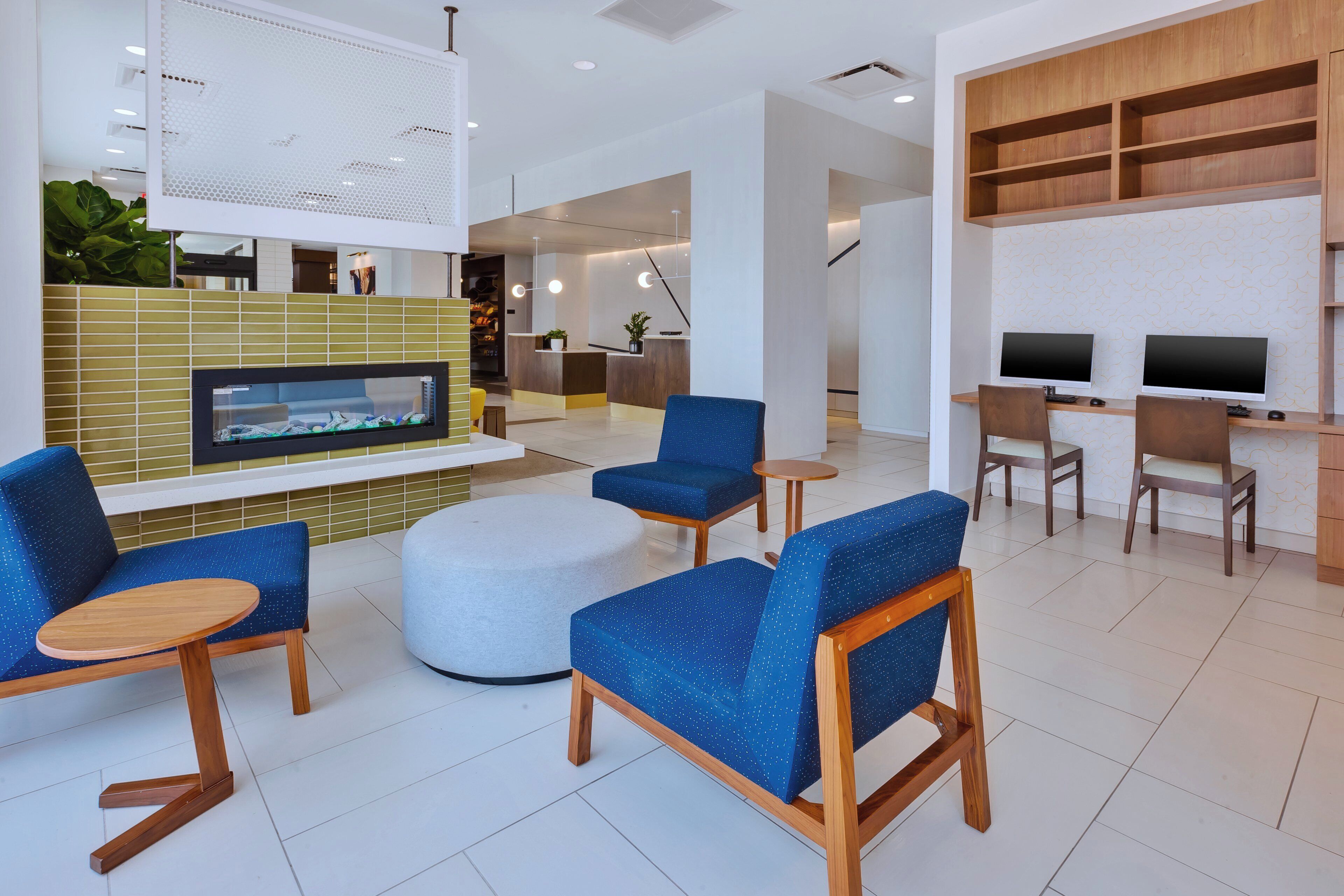 A modern lobby with seating, a fireplace, and a reception desk.