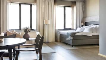 Una habitación de hotel con una cama, un sofá, una mesa de comedor y sillas.