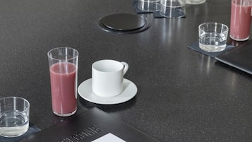 A conference table with a white notepad, a pen, and several glasses of water and juice.