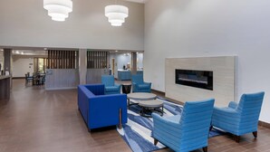 Eine großzügige Lobby mit Sitzgelegenheiten, einem Kamin und einem Fernseher an der Wand.