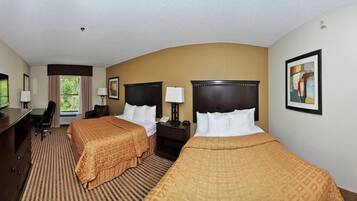 A hotel room with two beds, a desk, a chair, and a television.