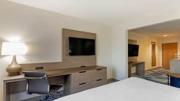 Une chambre d’hôtel comprenant un lit, un bureau avec une chaise, un téléviseur fixé au mur et une lampe.
