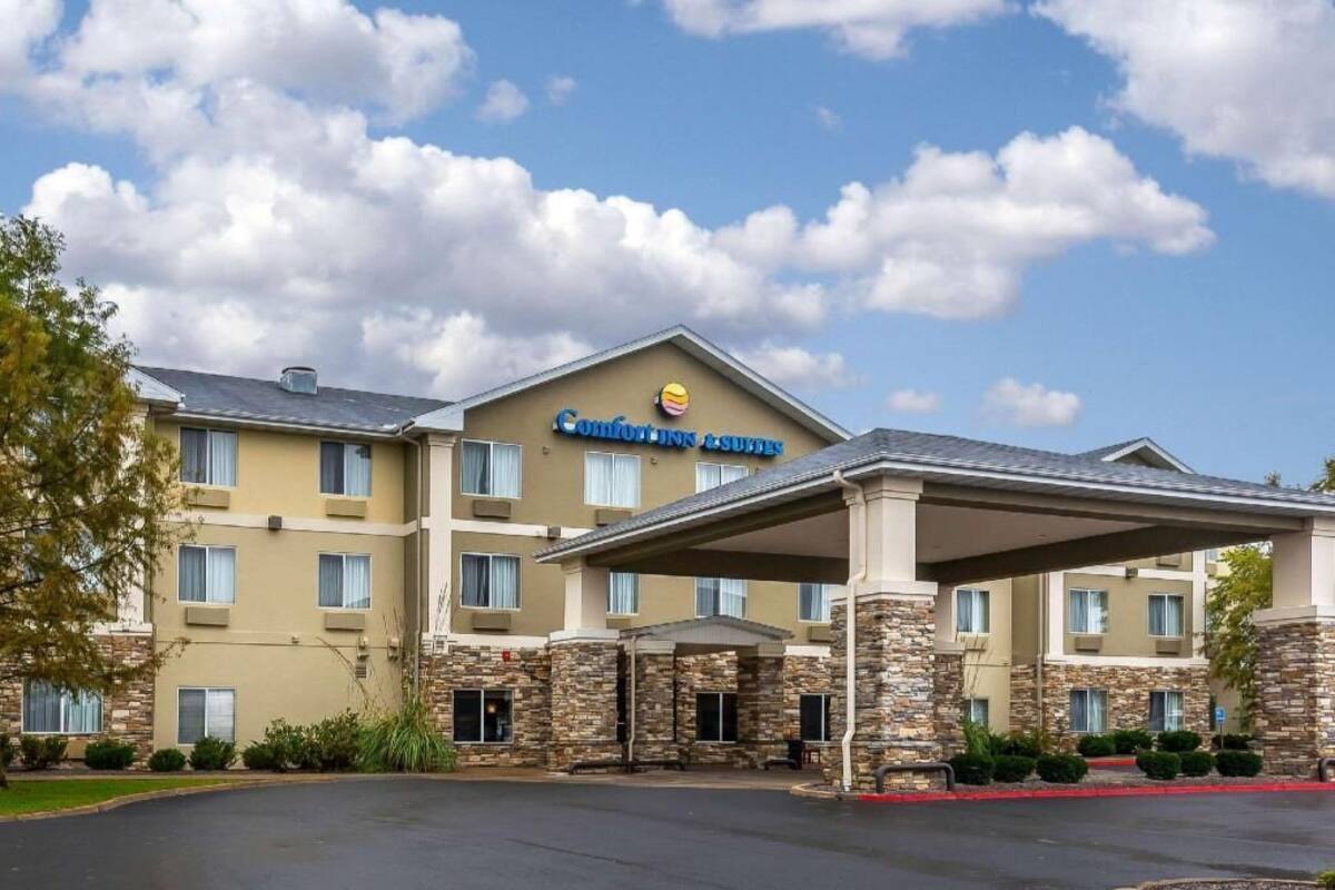 A hotel with a stone facade, a covered entrance, and a sign indicating it is a Comfort Inn & Suites.