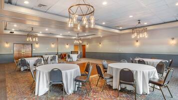 A conference room with round tables, chairs, and a patterned carpet.