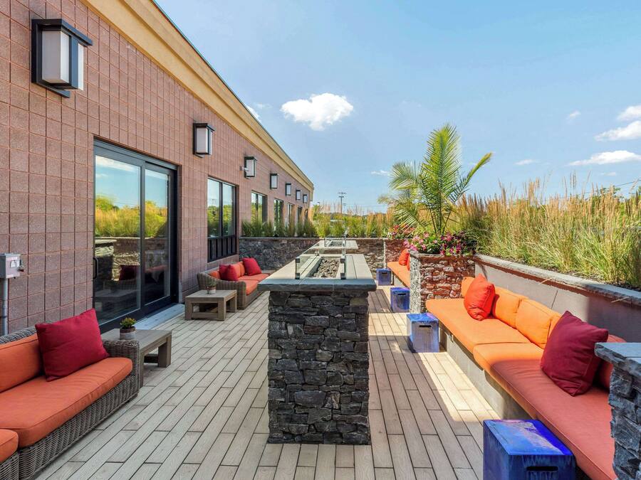 Un patio moderno al aire libre con paredes de piedra, un sofá naranja largo y un comedor.