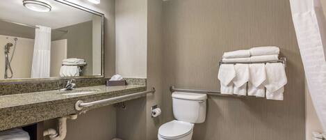A modern bathroom with a granite countertop sink, a toilet, a towel rack, and a mirror.
