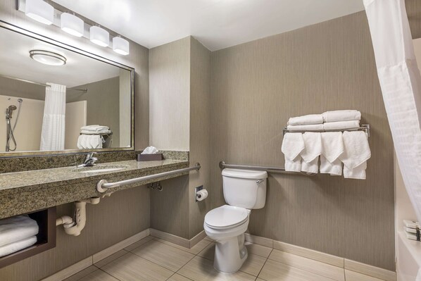 A modern bathroom with a granite countertop sink, a toilet, a towel rack, and a mirror.