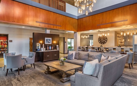 A spacious lobby with a high ceiling, wooden paneling, a large sofa, and a coffee table.