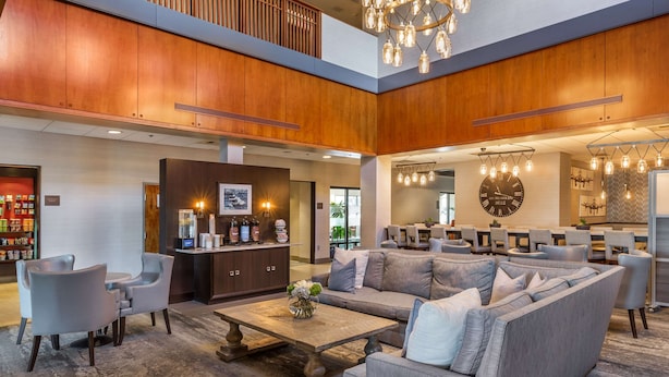 Un vestíbulo amplio con techo alto, paneles de madera, un sofá grande y una mesa de centro.