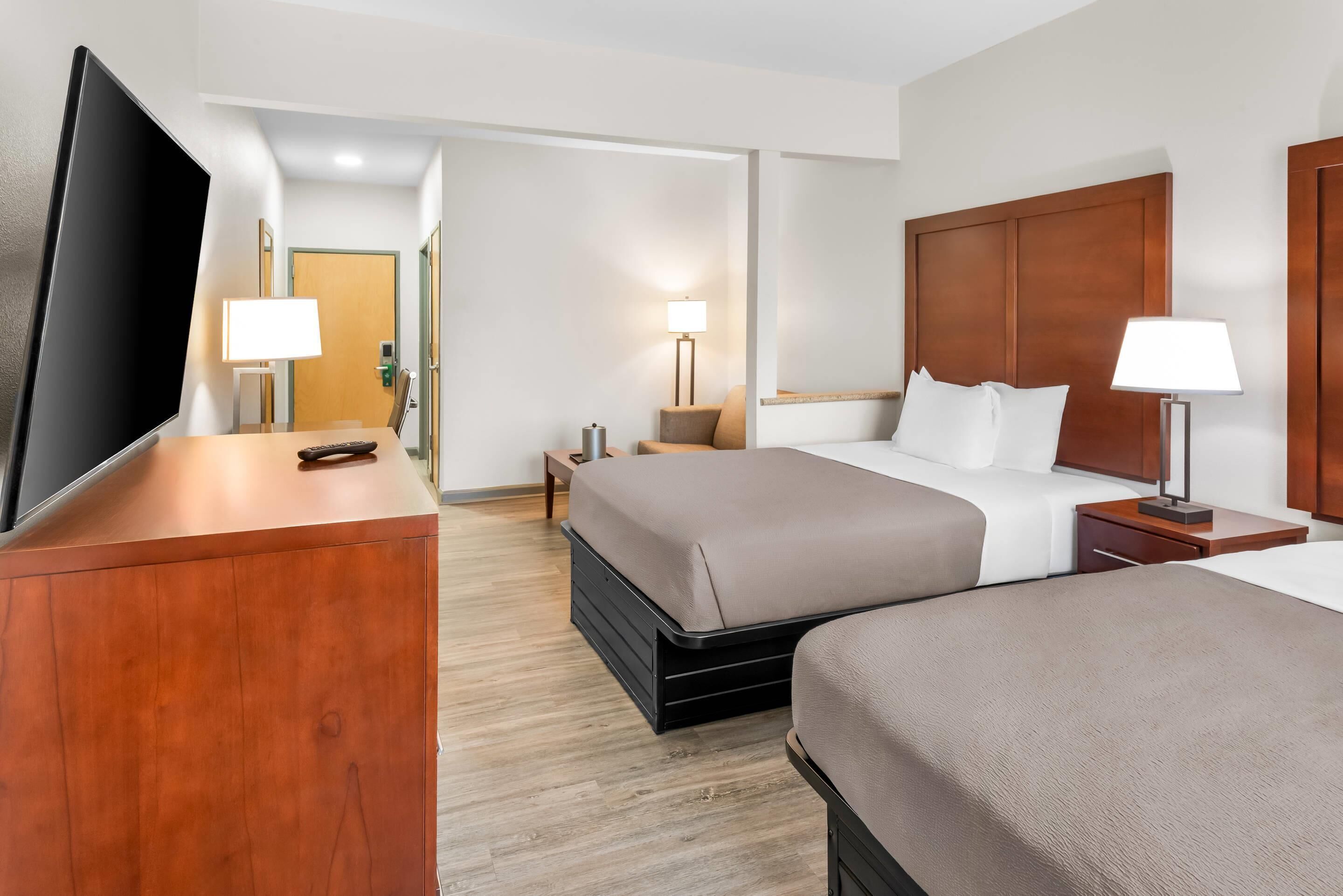 A hotel room with a bed, bedside tables, a TV, and a desk.