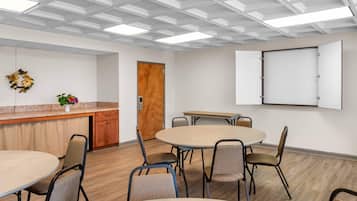 Un salón de conferencias con una mesa redonda, sillas, una pizarra y una puerta de madera.