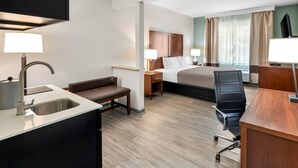 Ein Hotelzimmer mit Bett, Schreibtisch, Stuhl und einer kleinen Küchenzeile.