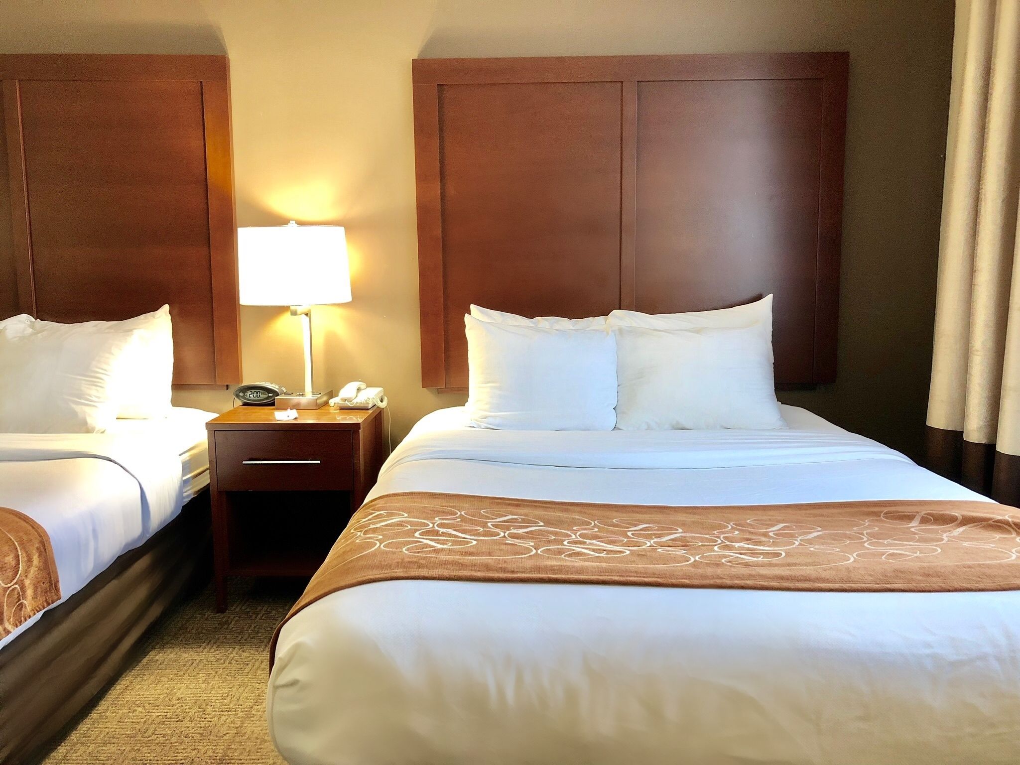 Une chambre d’hôtel avec deux lits, une table de chevet avec une lampe et un téléphone.