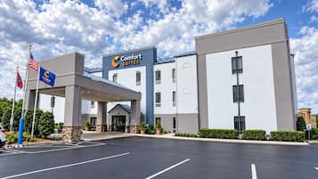 A Comfort Suites hotel with a covered entrance, multiple floors, and a parking lot.