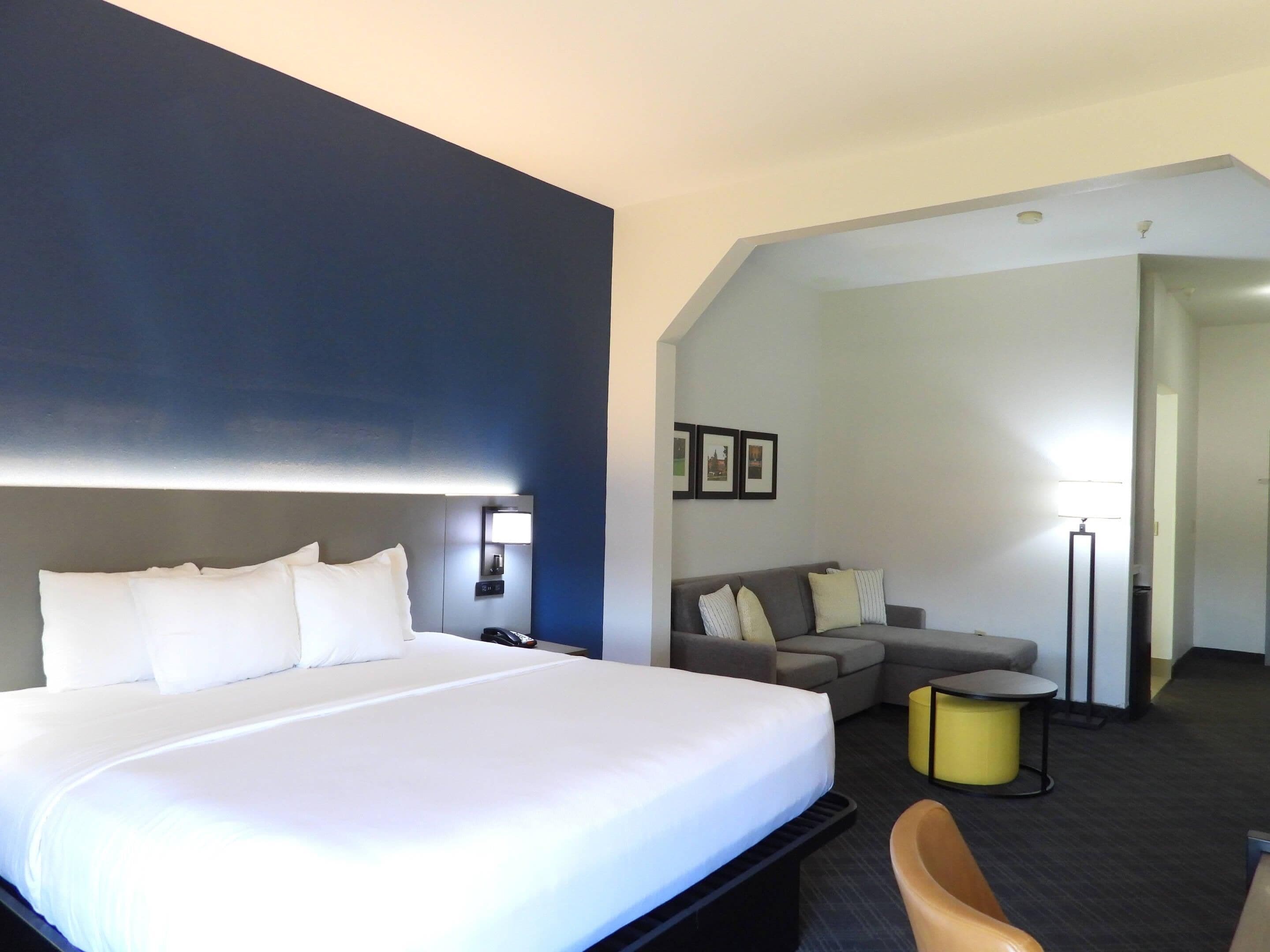 Een hotelkamer met een groot bed, een bank, een klein tafeltje en een lamp.