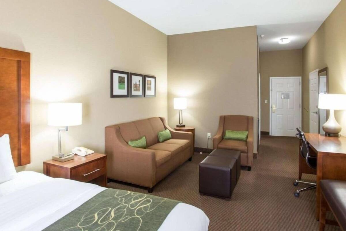Ein Hotelzimmer mit Bett, Sofa, Stuhl, Schreibtisch und Lampe.