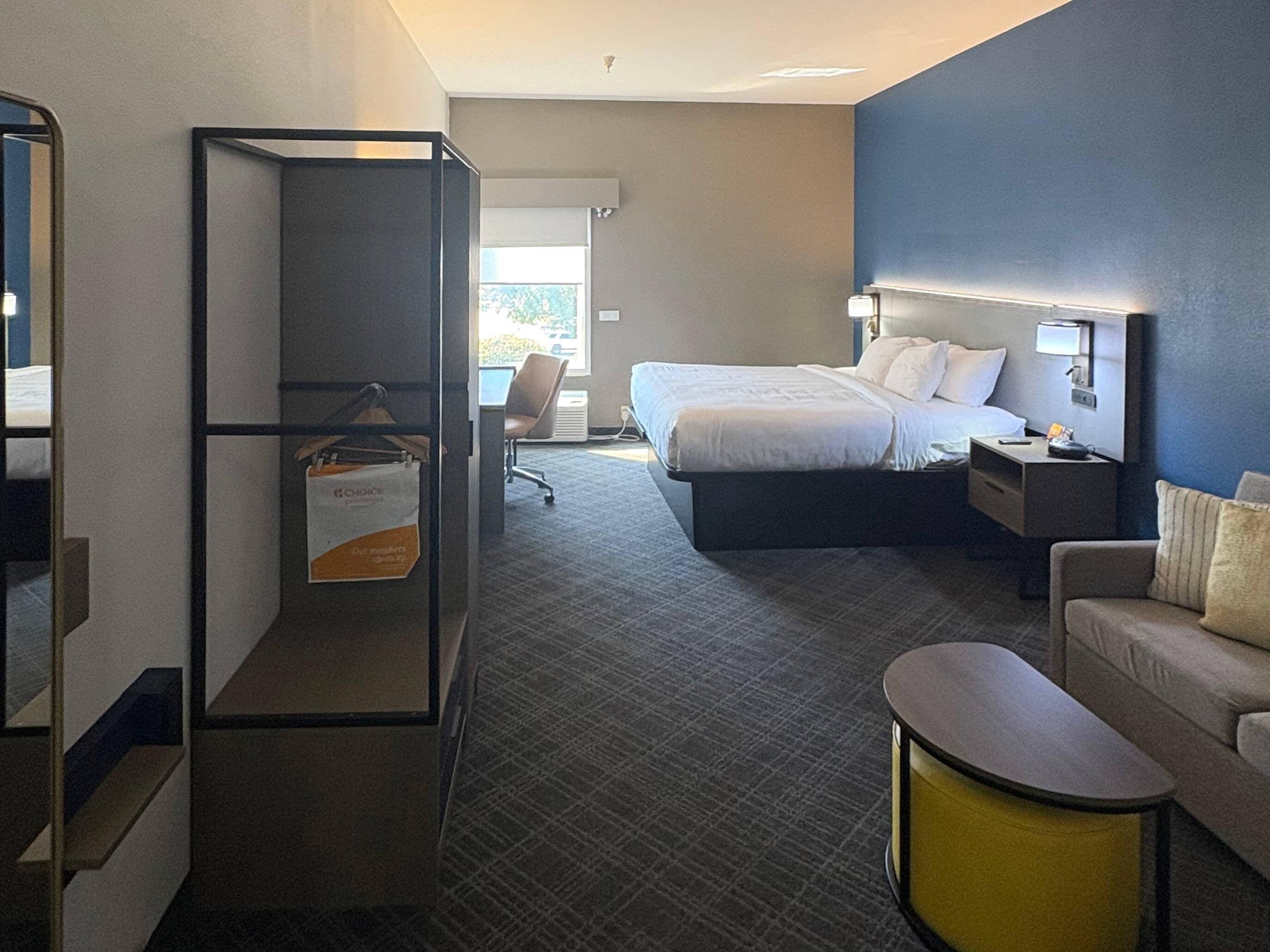 Una habitación de hotel con cama, escritorio, silla, sofá y una mesita.