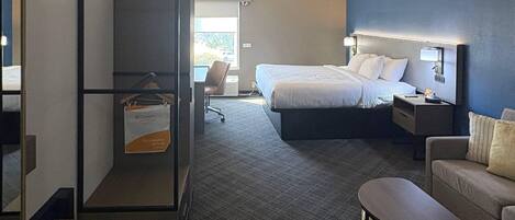 Una habitación de hotel con cama, escritorio, silla, sofá y una mesita.