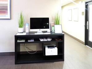 A reception desk with a desktop computer, two potted plants, and a printer. - Comfort Suites Crossville (Crossville)