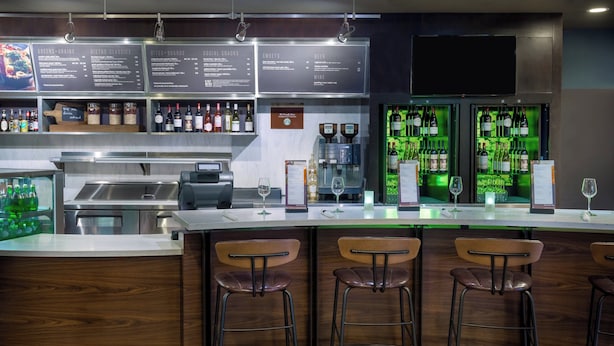 A bar area with a counter, stools, and a menu board. - Courtyard by Marriott Tallahassee North/I-10 Capital Circle (Tallahassee)