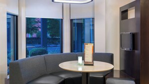 A modern seating area with a round table, cushioned seating, and a menu stand. - Courtyard by Marriott Tallahassee North/I-10 Capital Circle (Tallahassee)
